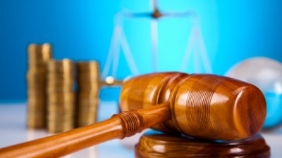 פטיש שופט מוכן על שולחן ומטבעות ומאזניים מאחורייו