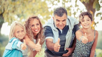 סבא והנכדים שלו בפארק מחייכים ומסמנים ok עם הבוהן של היד.