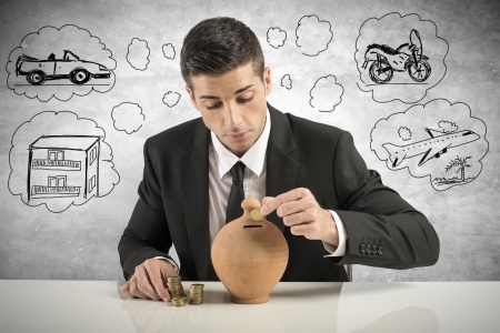 איש עסקים לובש חליפה משלשל מטבעות לתוך קופת חיסכון.