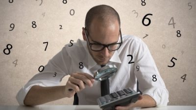 בחור צעיר עם עניבה מחזיק בידיו מחשבון וזכוכית מגדלת ומאחוריו רקע של מספרים על בד לבן ועורך מבדק פנסיוני מקיף.