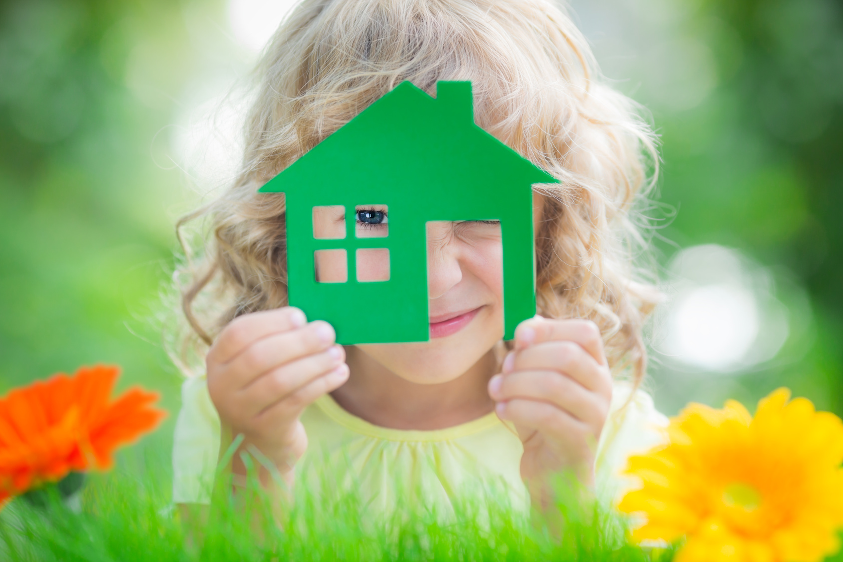 ילד מאושר מחזיק בית בידיים על רקע ירוק באביב