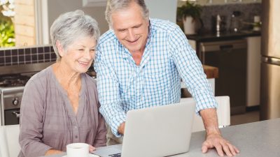 זוג מבוגא שמח מביט על הצעה משתלמת לביטוח משכנתא אחרי גיל 60