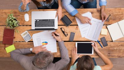 קבוצה של עצמאיים יושבים מסביב לשולחן וחושבים על איזה ביטוח וחיסכון פנסיוני כדאי להם לרכוש