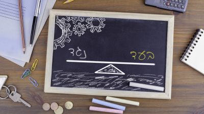 לוח גיר קטן מונח על שולחן עבודה ועליו ציור של מוזנאיים עם המילים בעד ונגד קופת גמל להשקעה