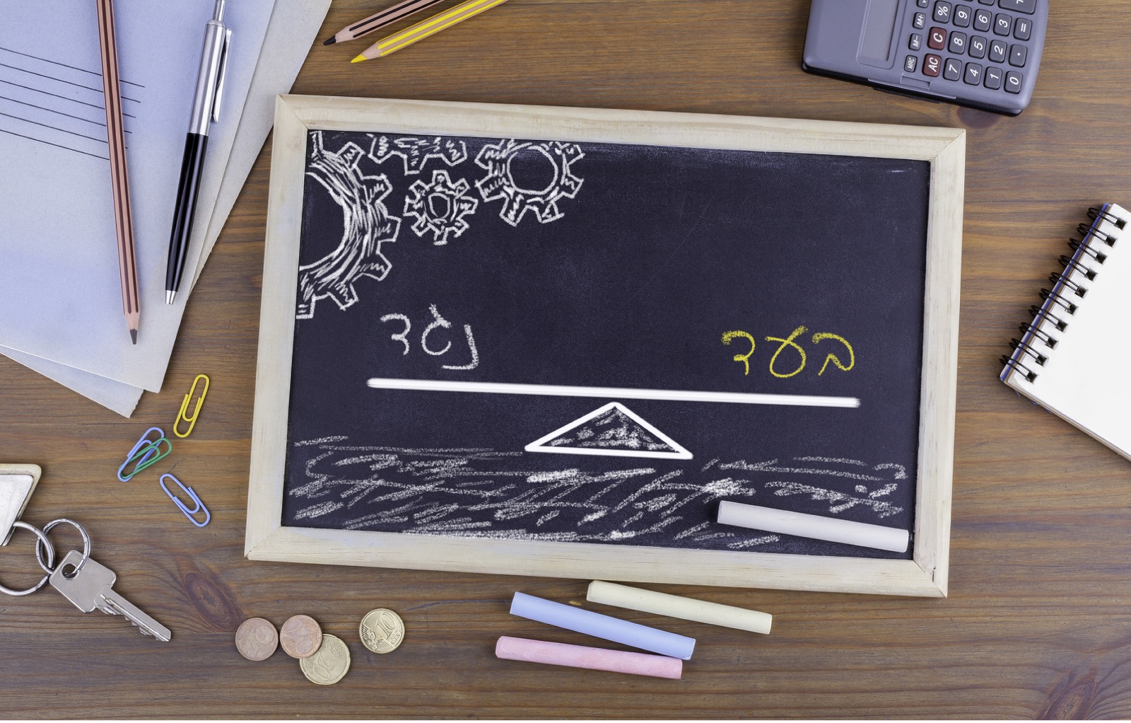 לוח גיר קטן מונח על שולחן עבודה ועליו ציור של מוזנאיים עם המילים בעד ונגד קופת גמל להשקעה