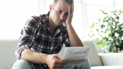 בחור תופס את הראש שמביט בכל הבלאגן שיש לו בתשלומי ביטוח היקרים לכן מחליט לעשות סדר בביטוחים