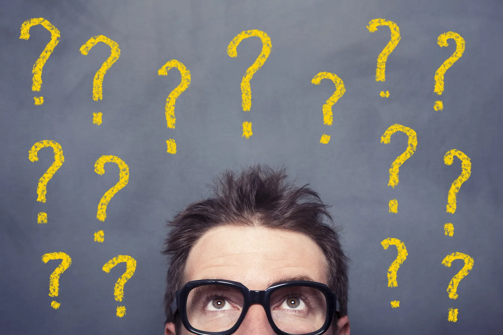 מלא סימני שאלה מצויירים על לוח ולפניו עומד אדם עם משקפיים ומנסה להבין איך לבחור קרן השתלמות