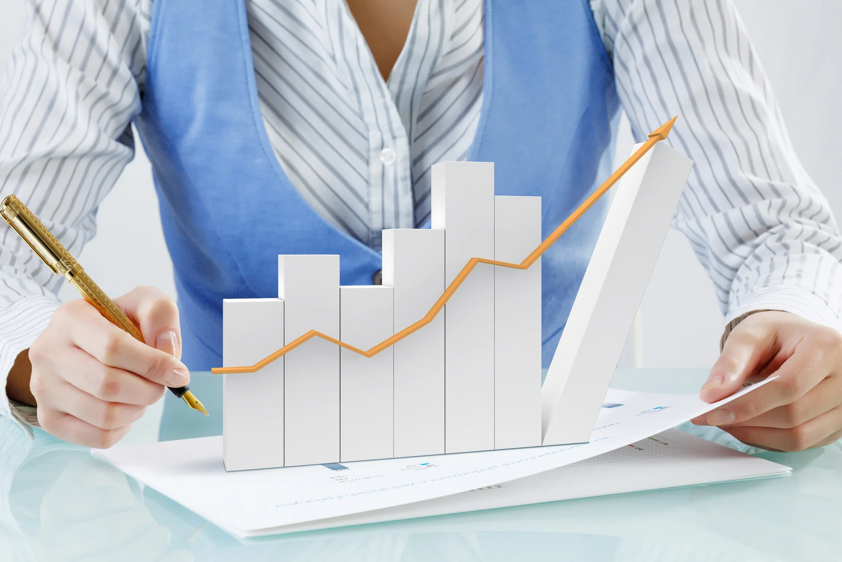 מומחית פיננסים המחזיקה ביד אחת עט מזהב ומציירת גרף