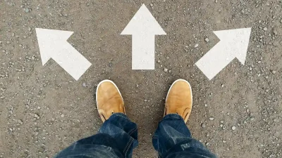 גבר עם מגפיים צהובות עומד על הכביש מול שימני דרך לשלושה כיוונים ותלבט מה לבחור